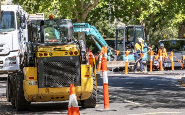 A road crew resurfacing an urban street beside traffic control signage